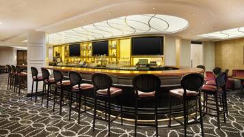 A bar area with a curved counter, multiple bar stools, and a patterned carpet.