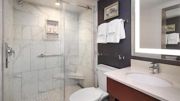 A bathroom with a glass-enclosed shower, a white toilet, a vanity with a sink, and a mirror.