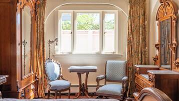 A room with a bed, a chair, a table, and a mirror.