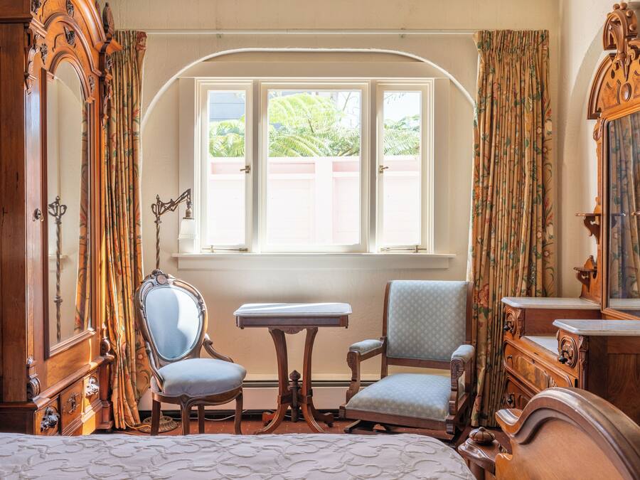 A room with a bed, a chair, a table, and a mirror.
