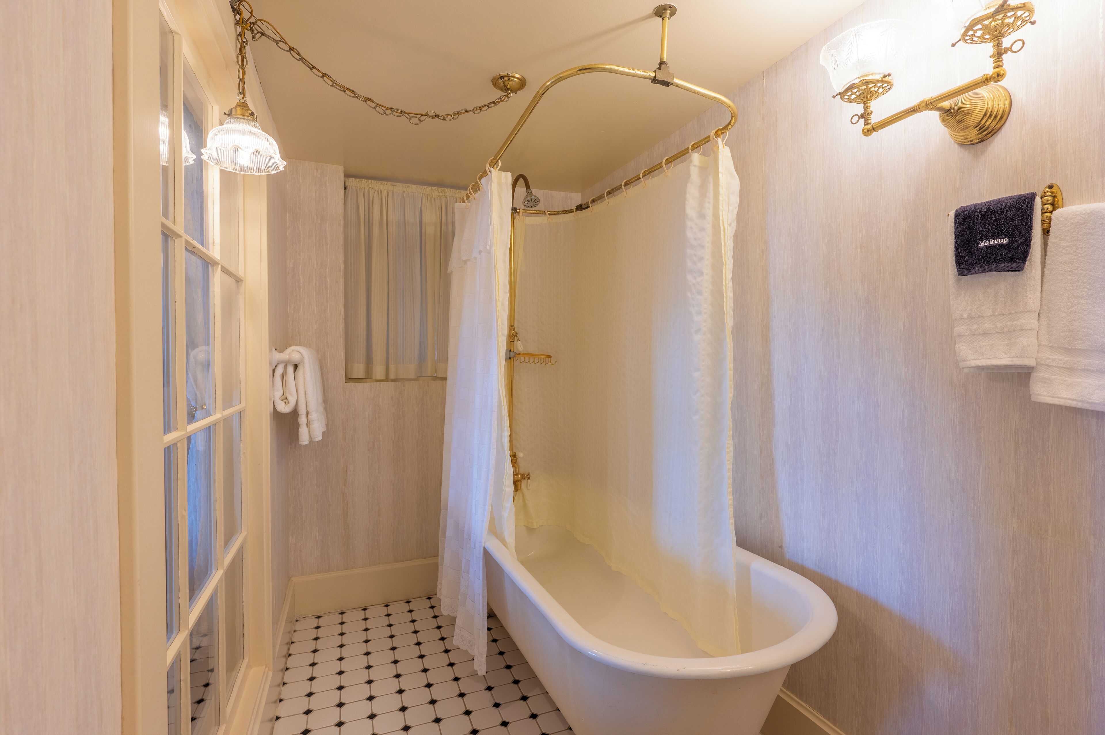 Une salle de bain avec une baignoire sur pieds, un rideau de douche et un porte-serviettes avec des serviettes.