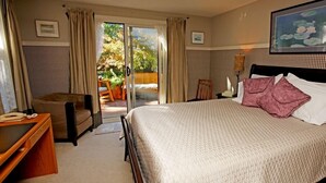 A hotel room with a bed, a desk, a chair, and a view of the outdoors. - Buffaloberry B&B (Banff)