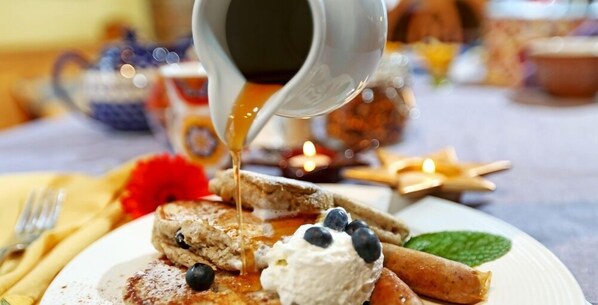 A breakfast plate with pancakes, blueberries, whipped cream, and syrup. - Buffaloberry B&B (Banff)