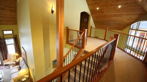 A spacious room with a high ceiling, a wooden staircase, and a large window providing natural light. - Buffaloberry B&B (Banff)