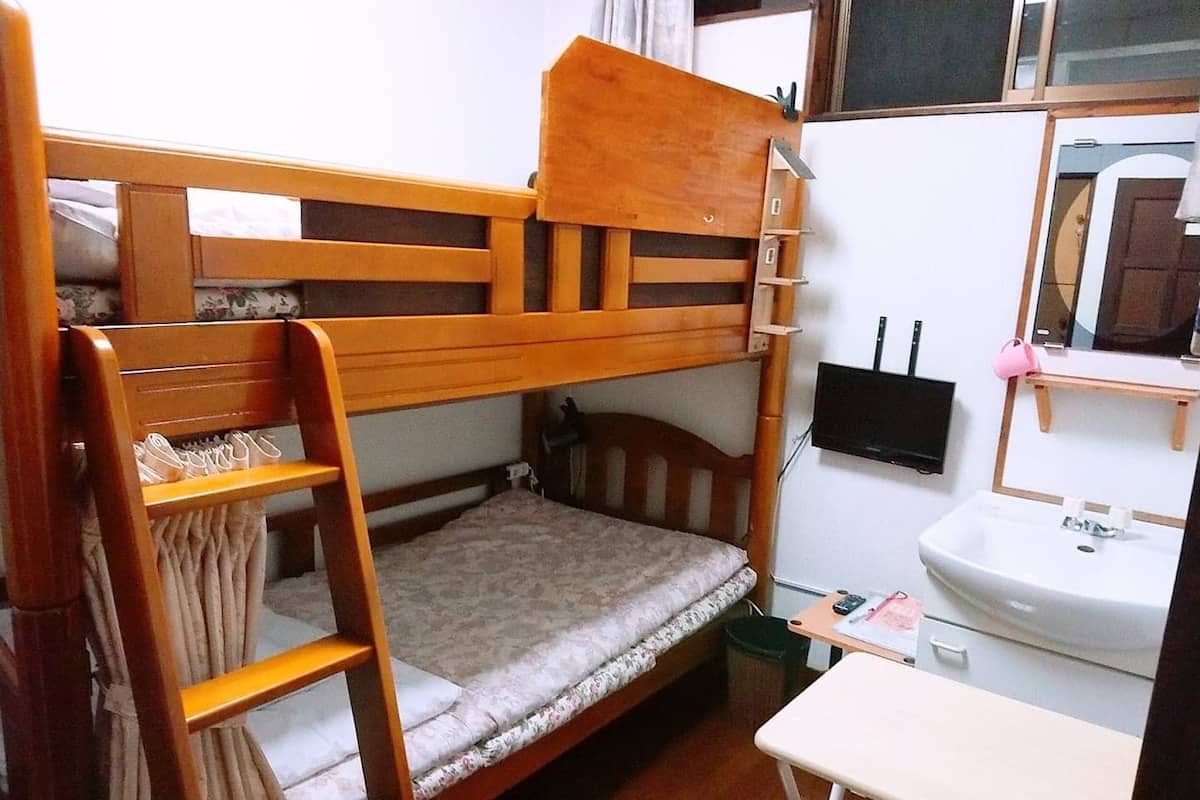Une petite pièce comprenant un lit superposé, un petit bureau, un lavabo et un miroir.