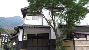 Ein traditionelles japanisches Gebäude mit einer schwarz-weißen Fassade, einer Holztreppe zum Eingang und einem Schild mit japanischen Schriftzeichen.