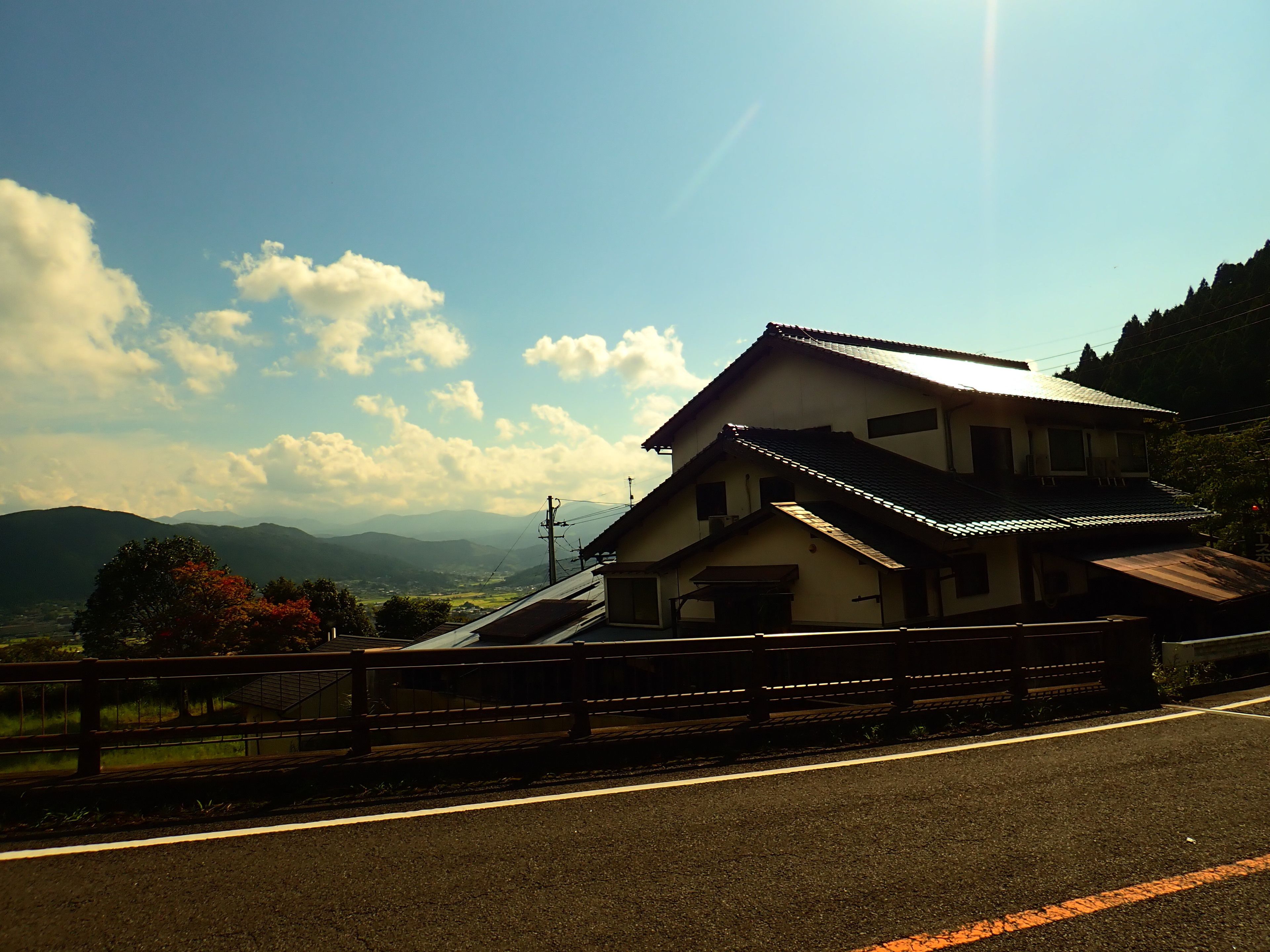 A two-story building with a sloped roof, located beside a road with a guardrail.
