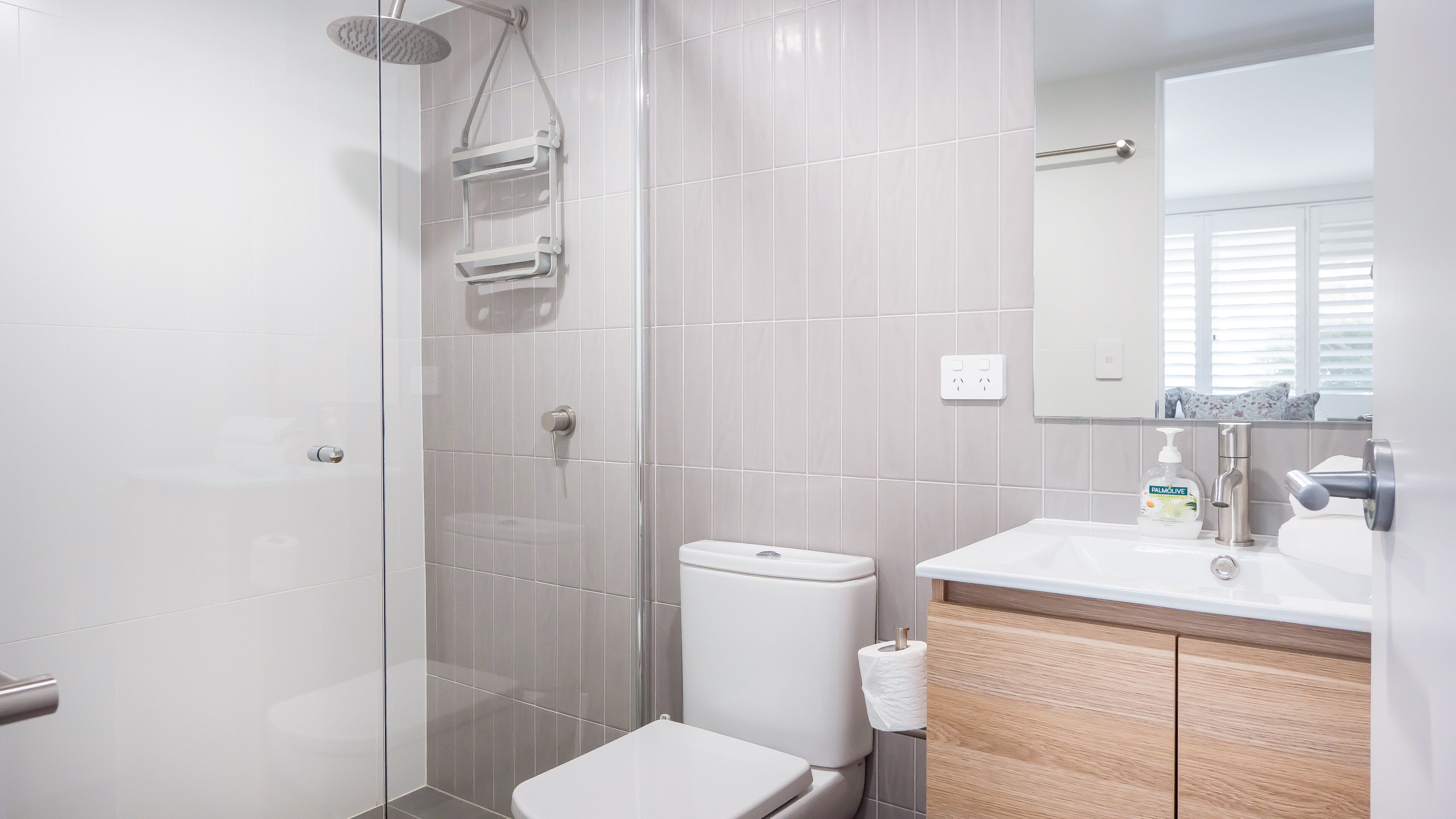 A modern bathroom with a toilet, shower, and sink.
