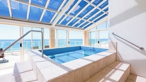 A modern indoor swimming pool with clear views of the ocean and a glass ceiling. - Viscount on the Beach (Surfers Paradise)