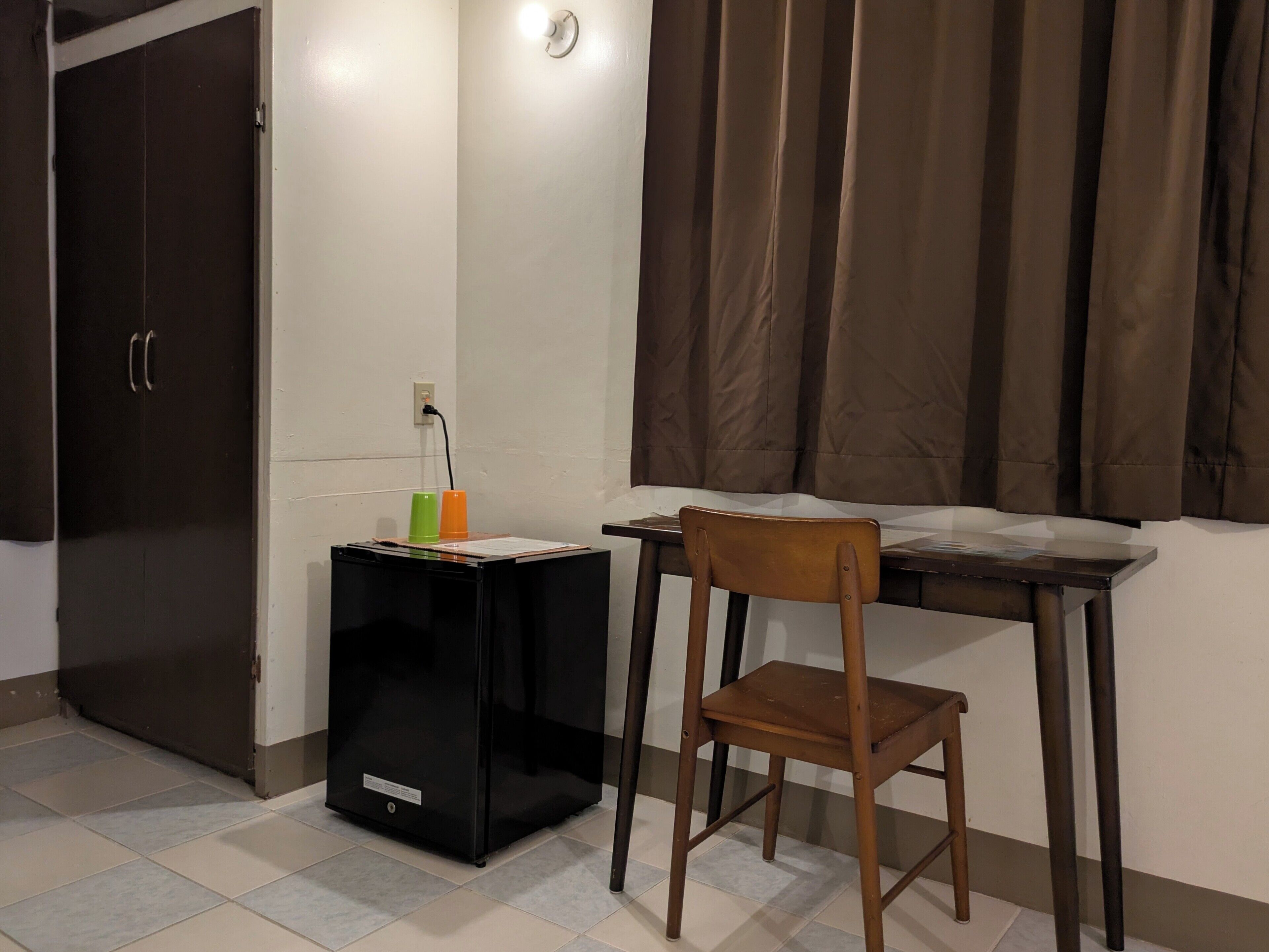 Una habitación pequeña con un escritorio, una silla y un armario negro.