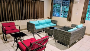 A room with a sofa set, two armchairs, a coffee table, and a window with curtains. - DW Motel Palau (Koror)