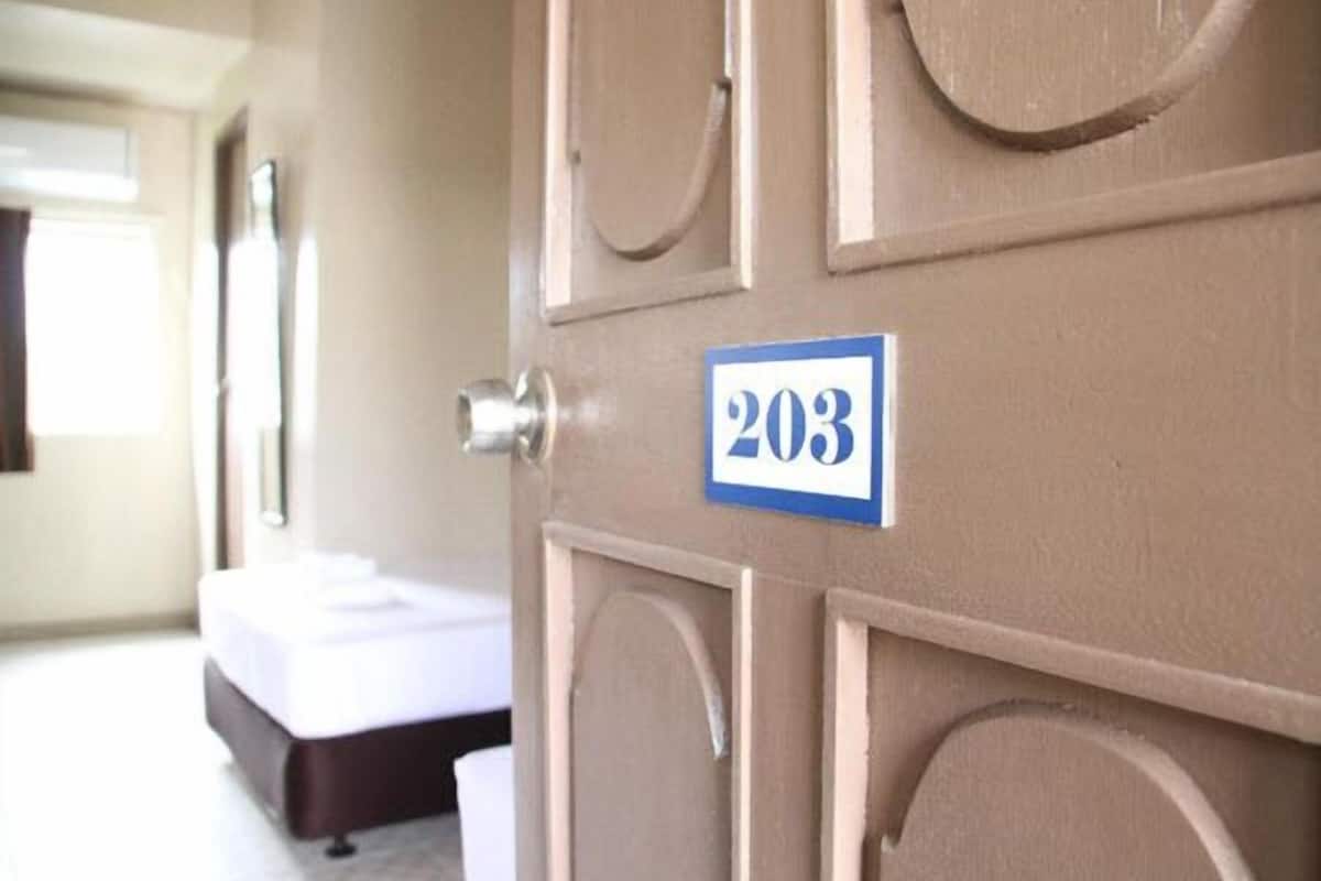 A hotel room door with the number 203 on it, a bed, and a window.