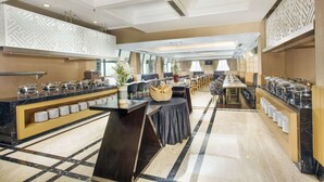 A spacious buffet area with multiple serving stations, a long dining table, and a decorative wall with geometric patterns. - Royal Kuningan Hotel (Jakarta)