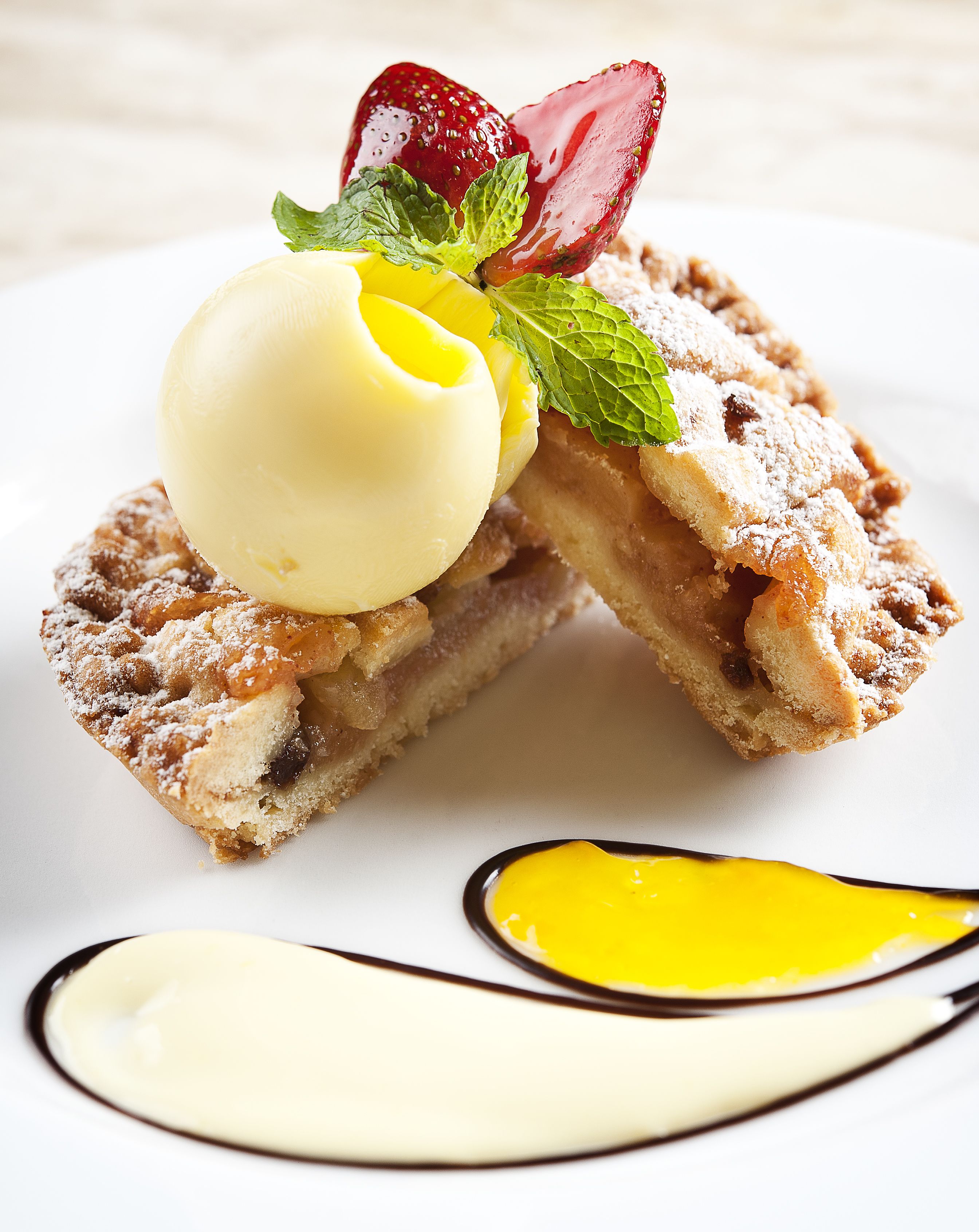 Ein Dessert mit Kuchenstück, einer Kugel Eis und einer Erdbeere.