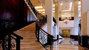 A grand staircase with ornate black railings and a chandelier above. - Royal Kuningan Hotel (Jakarta)