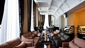 A spacious lobby with leather sofas, a coffee table, and a dessert display. - Royal Kuningan Hotel (Jakarta)