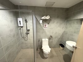 A bathroom with a shower, toilet, and sink, tiled walls, and a sign prohibiting smoking.