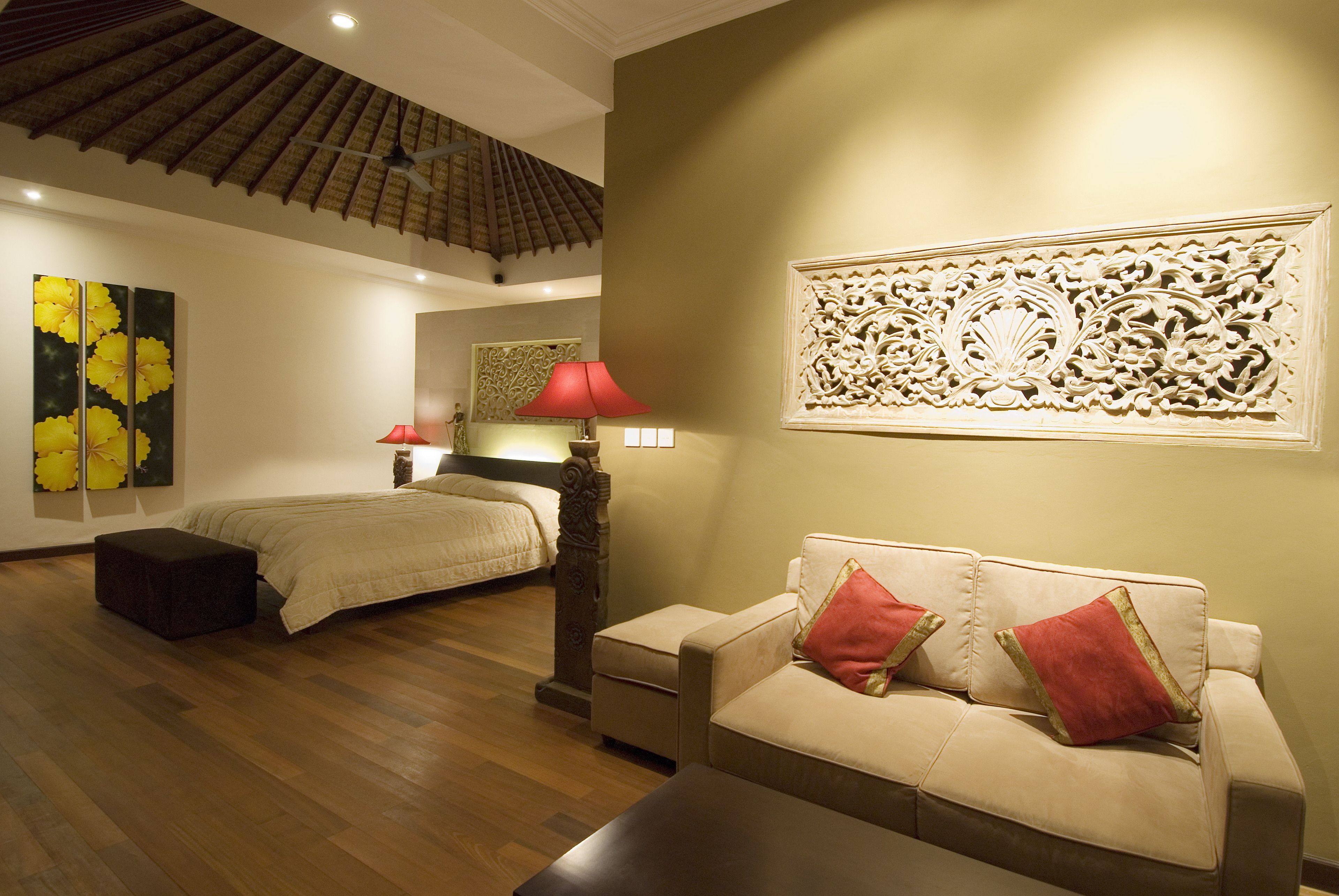 Ein Hotelzimmer mit Bett, Sofa, Nachttisch, Lampe und einer Wanddekoration.