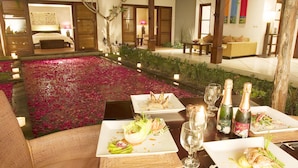 Un área de comedor al aire libre con mesas dispuestas para una comida, rodeada de un jardín con flores rosas y velas.