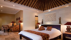 Un dormitorio amplio con una cama grande, un espacio de descanso con un sofá y sillas, y un adorno en la pared.