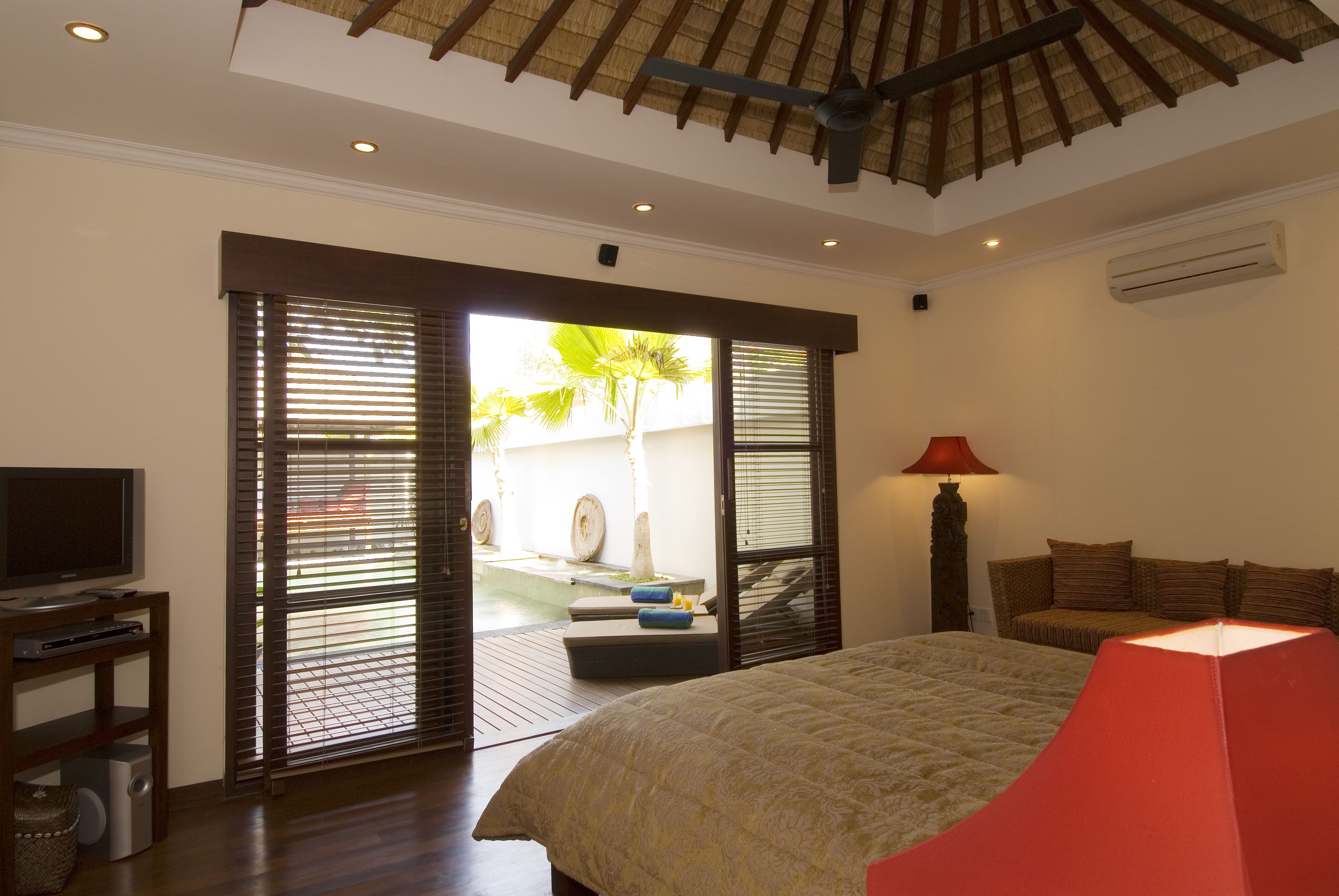A bedroom with a bed, a TV, and a red lamp.