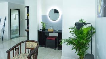 A modern bathroom with a round mirror, a sink, a chair, and a potted plant.