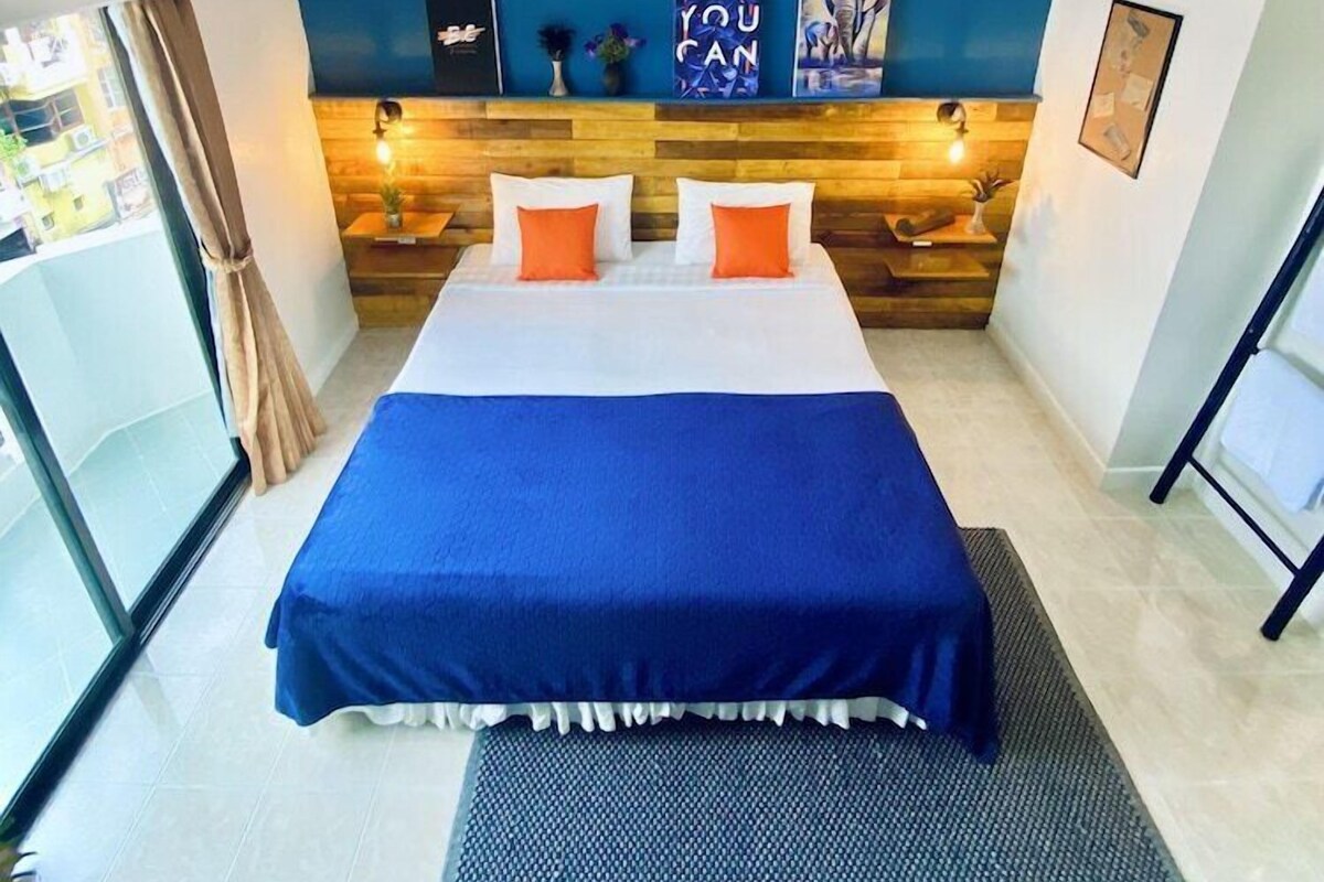 Una habitación de hotel con una cama, una pared azul y un ventanal.