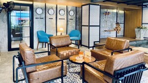 A modern lounge area with leather sofas, a glass partition, and clocks indicating different time zones. - BH Baan Paradise (Patong)