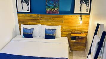 A hotel room with a large bed, wooden headboard, and artwork on the walls.
