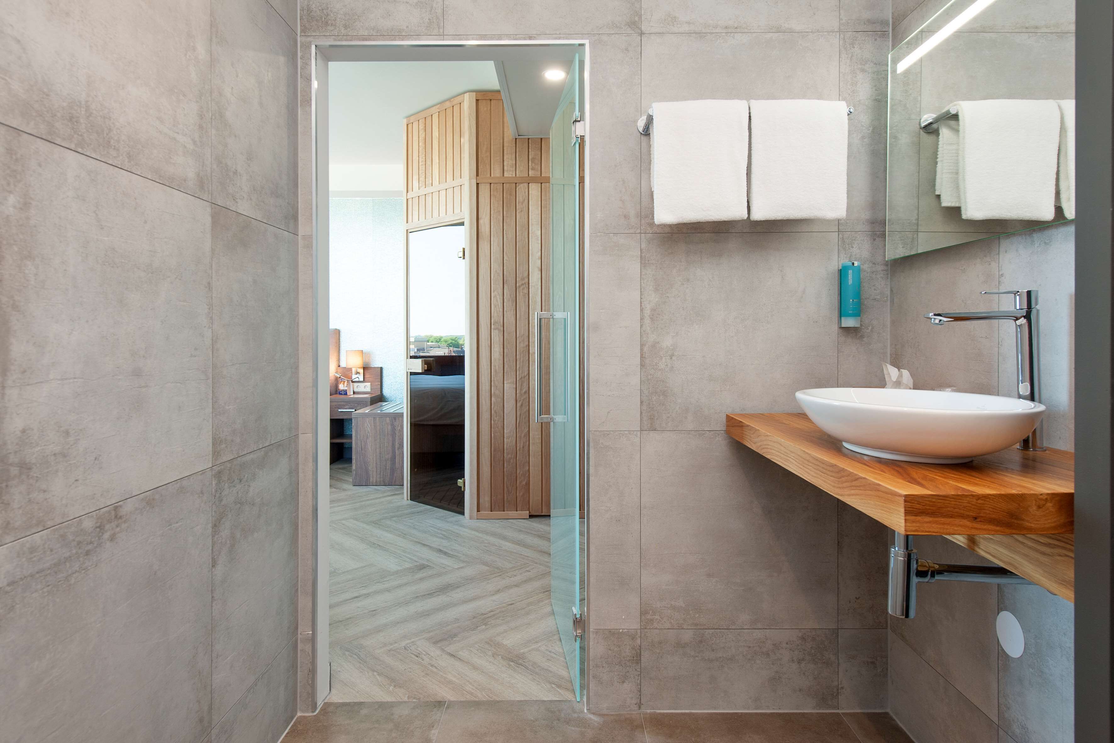 A modern bathroom with a large mirror, a wooden vanity, and a glass shower enclosure.