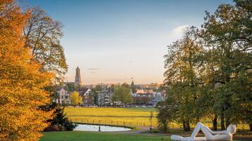 A park with a sculpture, a pond, and a distant building.
