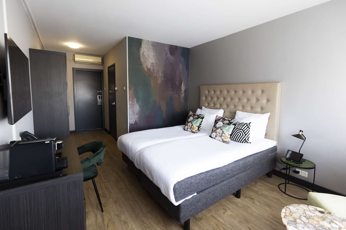 A modern hotel room with a large bed, a desk, and a chair.