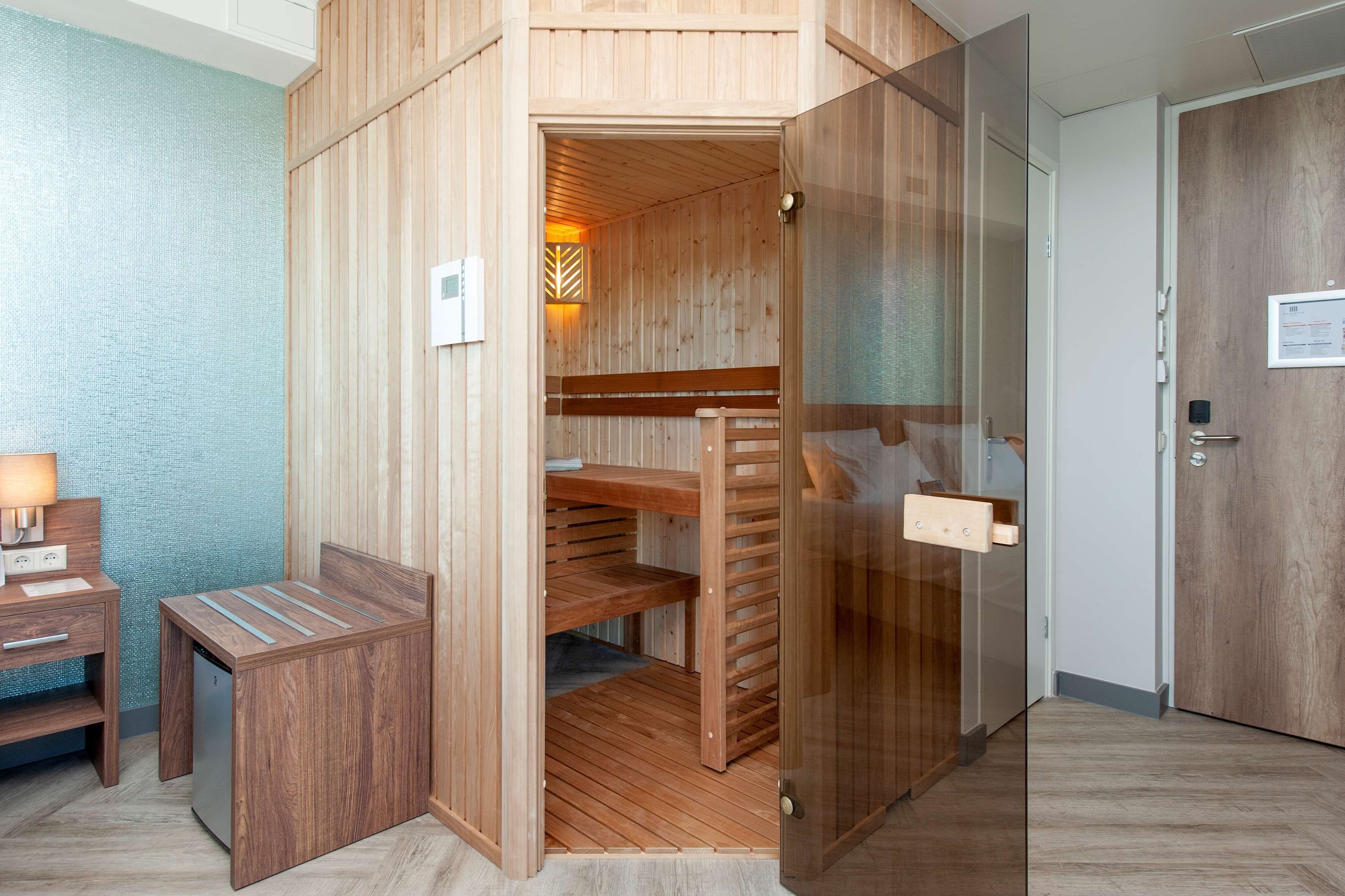A wooden sauna room with benches and a glass door.