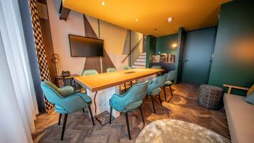 Un comedor moderno con una mesa de madera y sillas color turquesa, una escalera y una estantería.