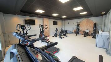 Une salle de sport équipée de tapis de course, de vélos elliptiques et de matériel de musculation.