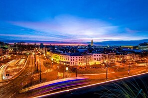 A cityscape at dusk with illuminated buildings and a prominent tower. - City Hotel Haarhuis - World Hotels Crafted Collections (Arnhem)