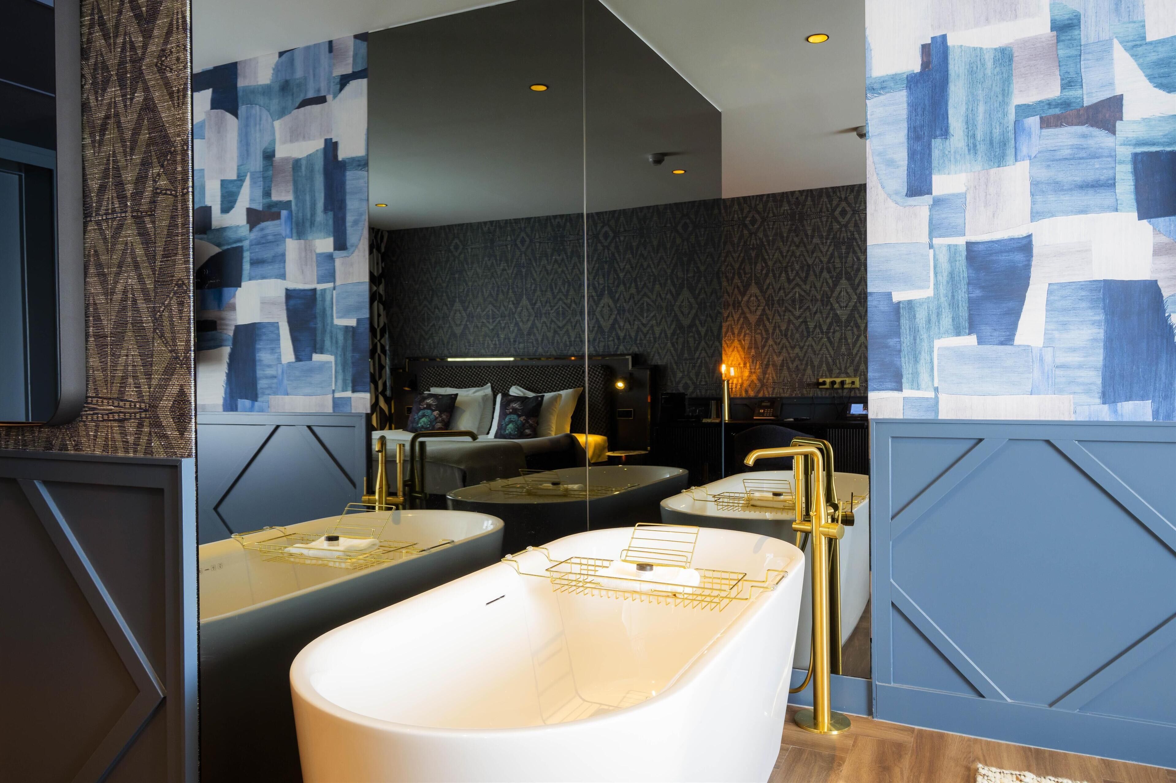 A modern bathroom with a freestanding bathtub, a vanity with a mirror, and a seating area with a sofa and side table.