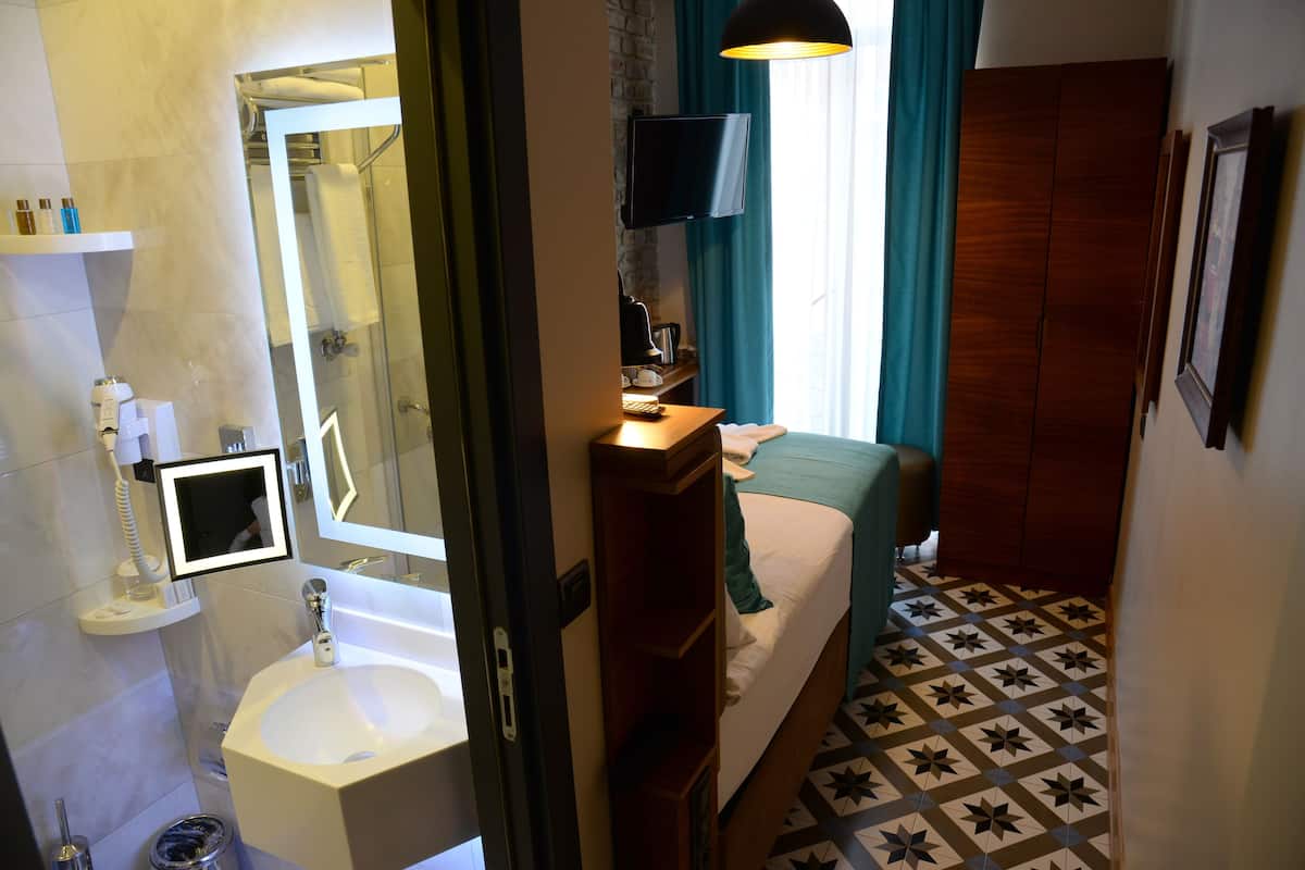 Une chambre d’hôtel avec salle de bain, un lit, une télévision et une armoire en bois.