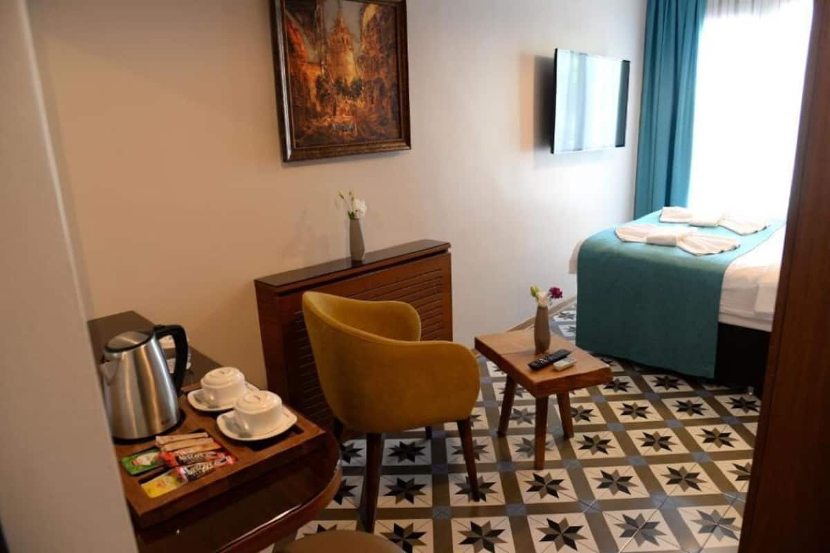 Une chambre d’hôtel avec un lit, un bureau doté d’une machine à café, une chaise et un tableau au mur.
