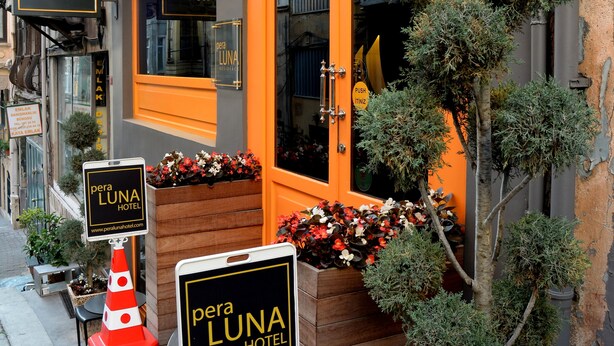 Perla Luna-hotellets exteriör kännetecknas av en framträdande orange fasad, stora fönster och krukväxter.