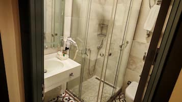 A modern bathroom with a glass-enclosed shower, a white sink, and a patterned floor.