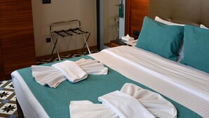 Ett hotellrum med en snyggt bäddad säng, en handduksställning och en väggmonterad luftkonditioneringsanläggning.