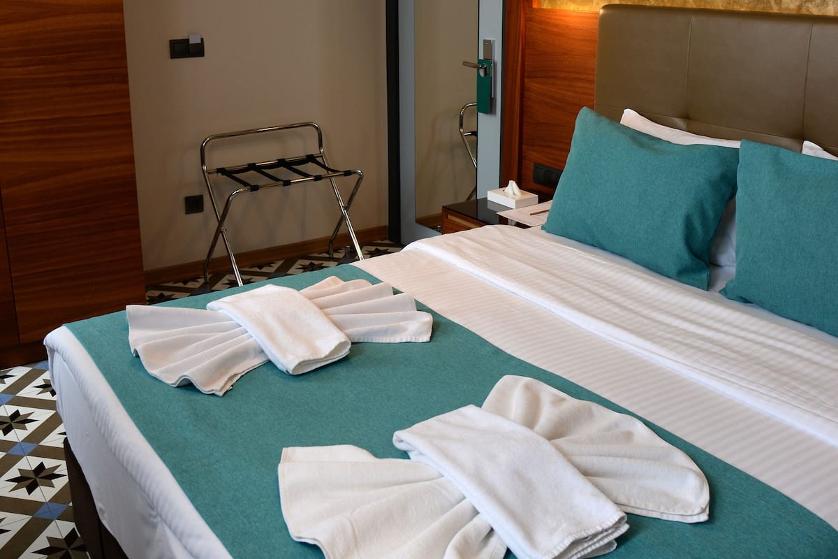 Une chambre d’hôtel avec un lit bien fait, un porte-serviettes et un climatiseur fixé au mur.