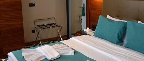 A hotel room with a neatly made bed, a towel rack, and a wall-mounted air conditioner.