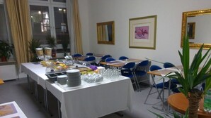 Une salle de conférence avec une longue table préparée pour une réunion, entourée de chaises, et une fenêtre avec des rideaux.