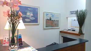 Un comptoir d’accueil avec une carte, des tableaux encadrés et un vase de fleurs.