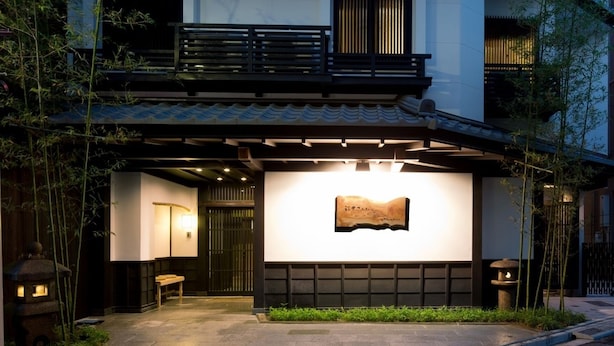 A modern building with a traditional Japanese entrance, a wooden bench, and a stone lantern. - The Edo Sakura (Tokyo)