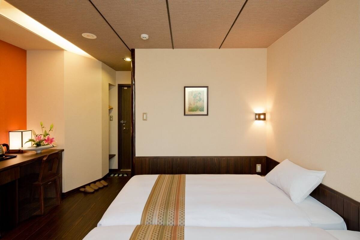 Una habitación de hotel con una cama, un escritorio con una lámpara y un cuadro en la pared.