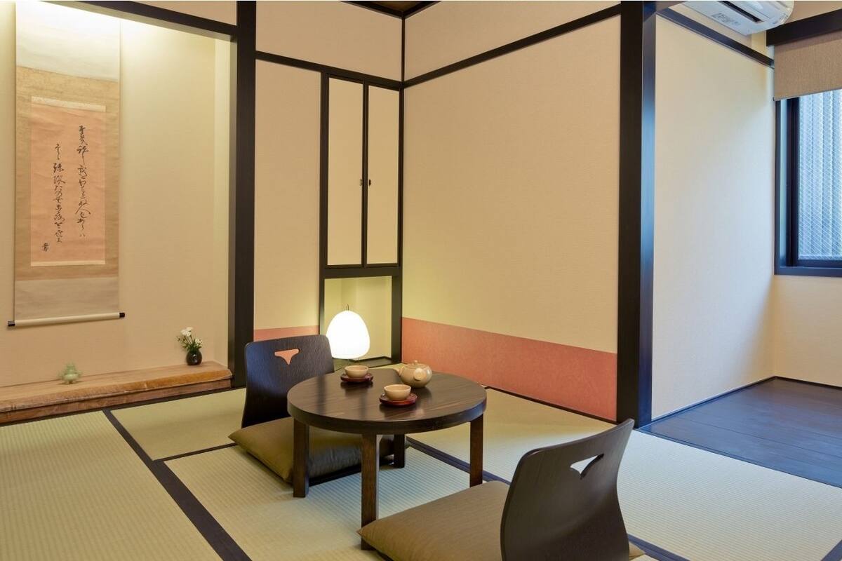Una habitación japonesa tradicional con suelo de tatami, una mesa baja con un juego de té y una puerta corredera.
