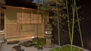 A traditional Japanese garden with a wooden building, stone lantern, bamboo, and moss. - The Edo Sakura (Tokyo)
